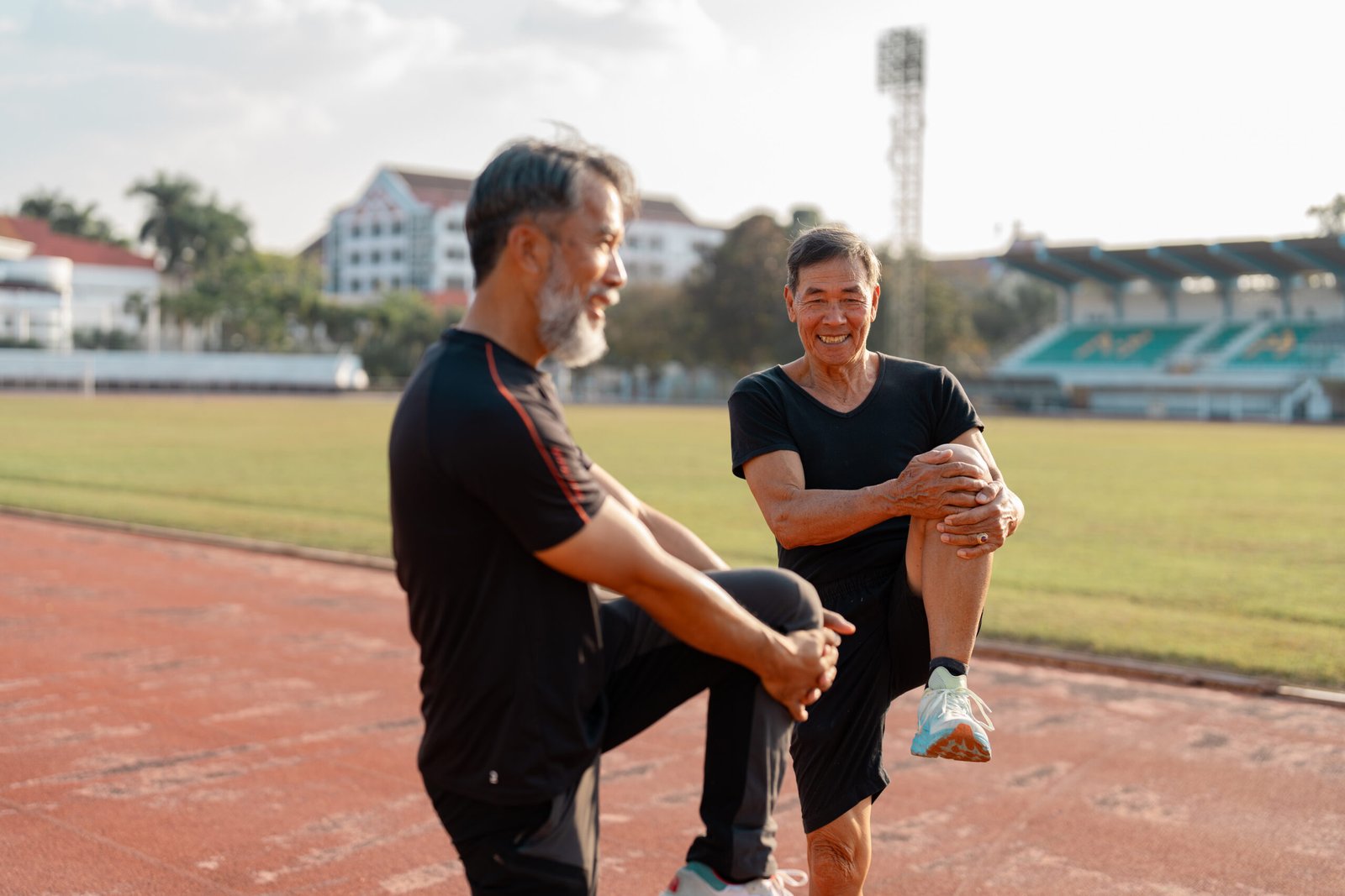 Wellness and fitness for seniors joyful men stretching on a track.